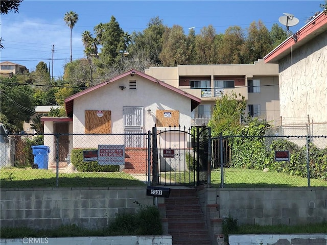 view of front of house featuring stucco siding, a gate, a front yard, and a fenced front yard