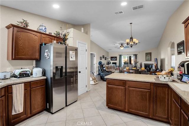 kitchen with stainless steel refrigerator with ice dispenser, pendant lighting, vaulted ceiling, light tile patterned floors, and ceiling fan with notable chandelier