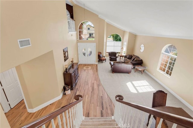 stairs featuring wood-type flooring, crown molding, and a towering ceiling