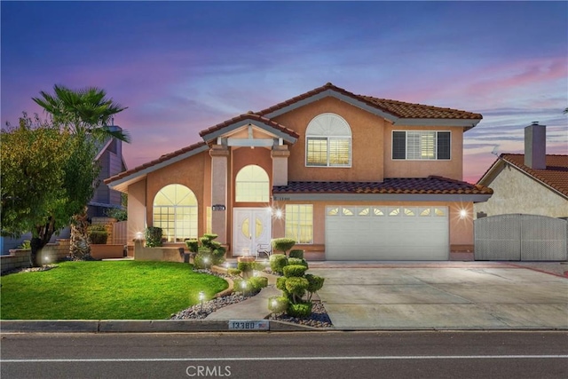 mediterranean / spanish-style home with a lawn and a garage