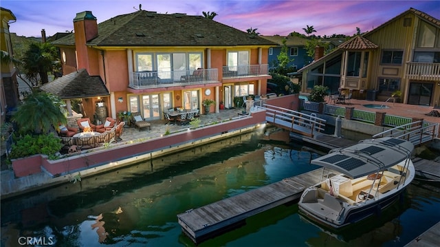 back house at dusk with a balcony and a patio area