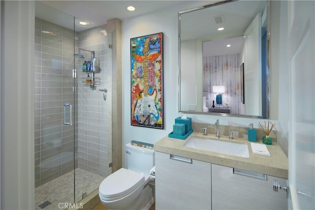 bathroom featuring a shower with door, vanity, and toilet