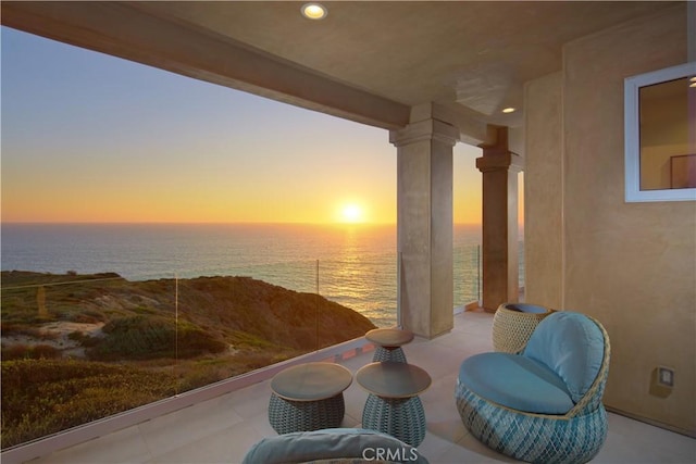 patio terrace at dusk featuring a water view