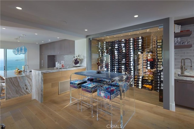 wine area featuring sink, light hardwood / wood-style floors, and an inviting chandelier