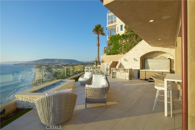 view of patio with area for grilling, a mountain view, a bar, and an outdoor fire pit