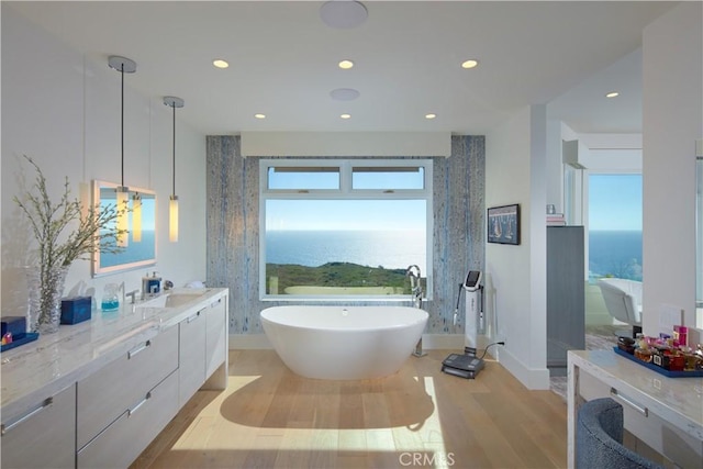 bathroom featuring a tub, vanity, a water view, and hardwood / wood-style flooring