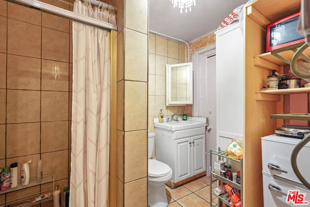 bathroom with tile flooring, toilet, vanity, and tile walls