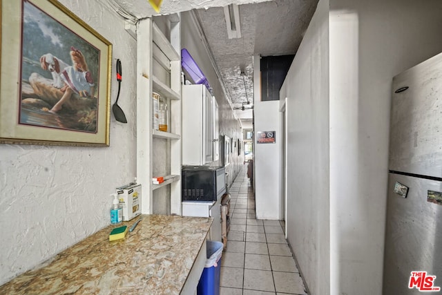 kitchen featuring water heater and light tile floors