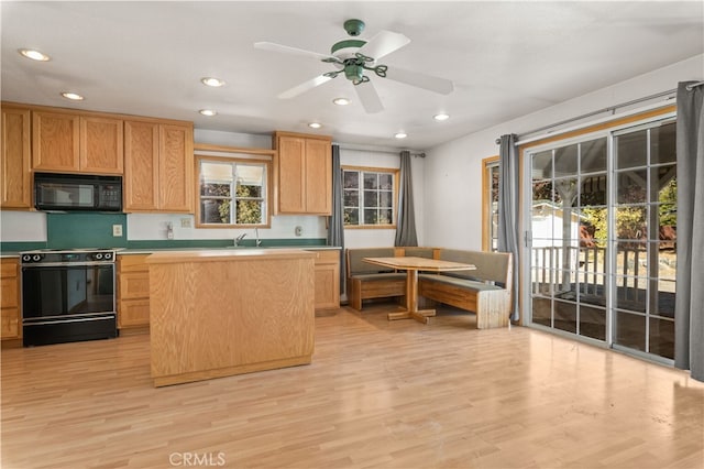 kitchen with range with electric stovetop, a kitchen island, ceiling fan, and light hardwood / wood-style flooring