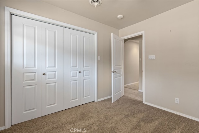 unfurnished bedroom with a closet and light colored carpet