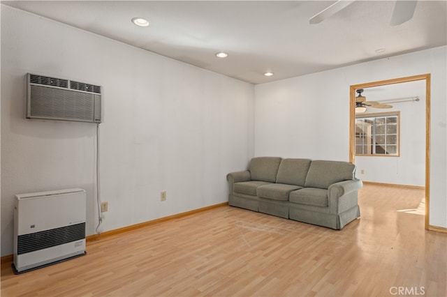 living room featuring an AC wall unit, ceiling fan, and light wood-type flooring