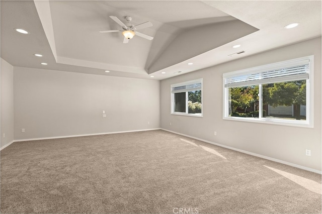 carpeted empty room with ceiling fan, a tray ceiling, and lofted ceiling