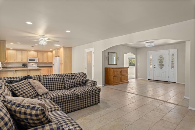 tiled living room featuring ceiling fan and sink