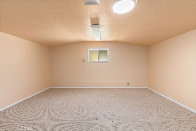 carpeted spare room with a textured ceiling and lofted ceiling