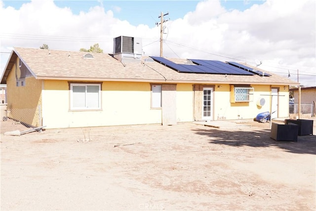 rear view of house featuring central AC and solar panels