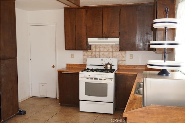 kitchen with decorative backsplash, dark brown cabinetry, white range with gas stovetop, and light tile patterned floors