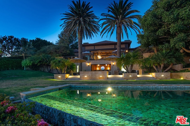 pool at dusk with a patio area and a yard