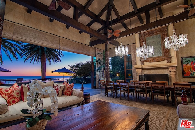 living room featuring ceiling fan with notable chandelier, a premium fireplace, beam ceiling, and high vaulted ceiling