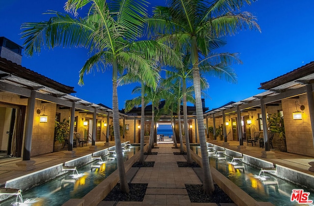 pool at twilight with pool water feature and a patio area