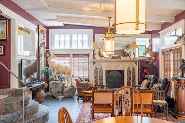 dining room featuring a fireplace, a healthy amount of sunlight, wood ceiling, and vaulted ceiling with beams