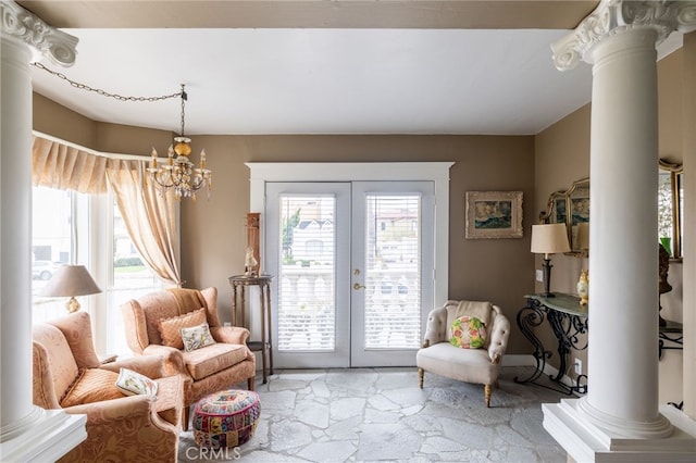 living room featuring ornate columns, a chandelier, and french doors