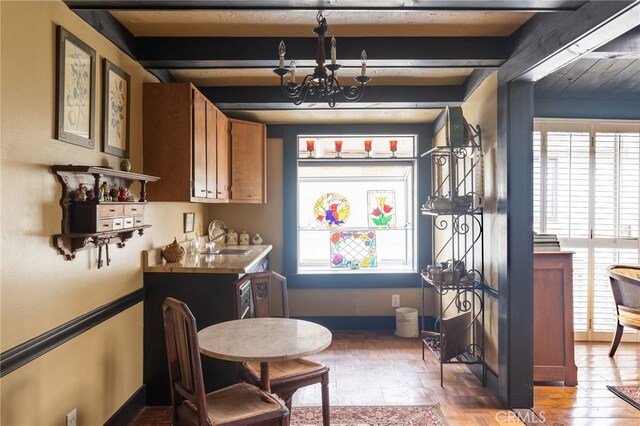 interior space featuring a healthy amount of sunlight, sink, a chandelier, and beamed ceiling