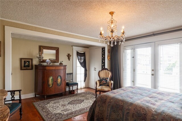 bedroom with dark wood-type flooring, a textured ceiling, access to exterior, and a notable chandelier