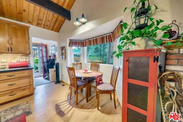 dining space featuring light wood-type flooring, lofted ceiling with beams, a healthy amount of sunlight, and wood ceiling