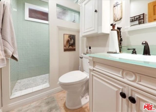 bathroom featuring tiled shower, vanity, and toilet