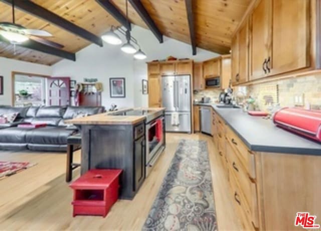 kitchen featuring ceiling fan, lofted ceiling with beams, light hardwood / wood-style floors, a kitchen island, and appliances with stainless steel finishes