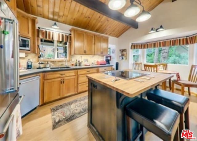 kitchen with vaulted ceiling with beams, wood ceiling, butcher block counters, and appliances with stainless steel finishes