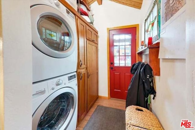 laundry area featuring cabinets, stacked washing maching and dryer, and light wood-type flooring