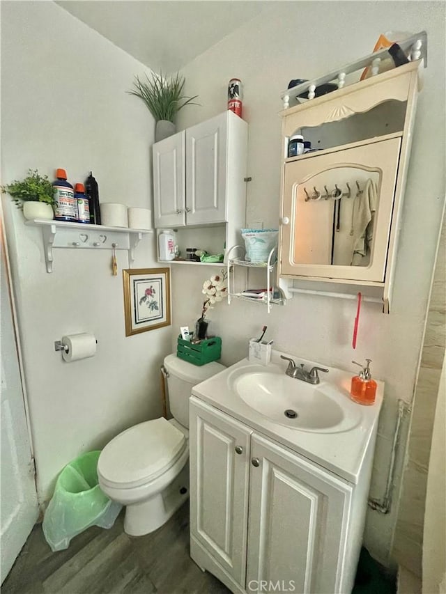 bathroom with hardwood / wood-style flooring, toilet, and vanity