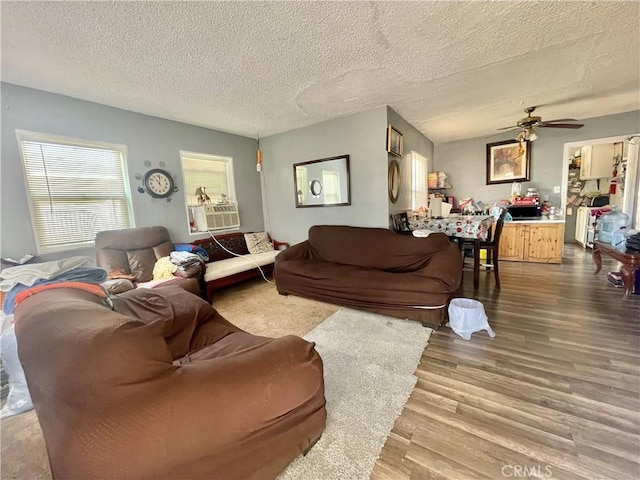 living room with ceiling fan, cooling unit, a textured ceiling, and hardwood / wood-style floors