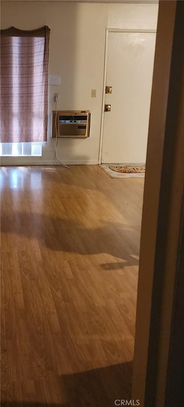 hallway with a wall unit AC and hardwood / wood-style flooring