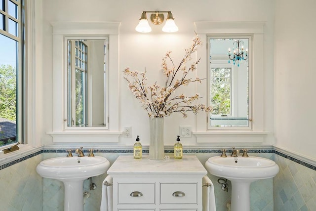 bathroom featuring tile walls, double sink, and a notable chandelier