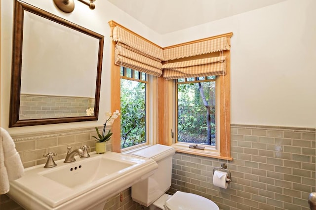 bathroom with toilet, tile walls, and sink