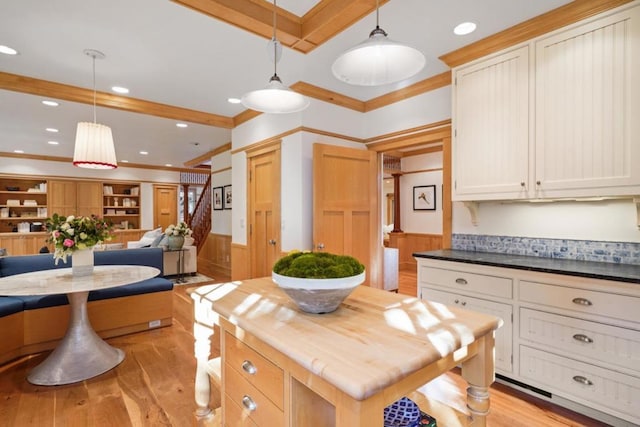 kitchen featuring a kitchen island, ornamental molding, butcher block countertops, and decorative light fixtures