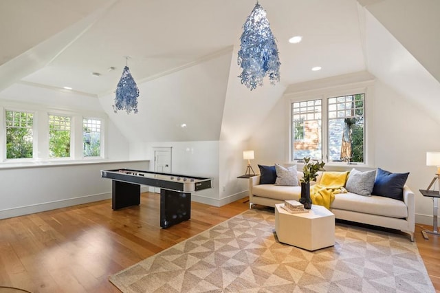 rec room featuring vaulted ceiling, plenty of natural light, crown molding, and light hardwood / wood-style flooring