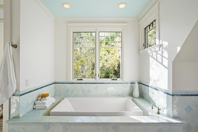 bathroom with ornamental molding and a relaxing tiled tub