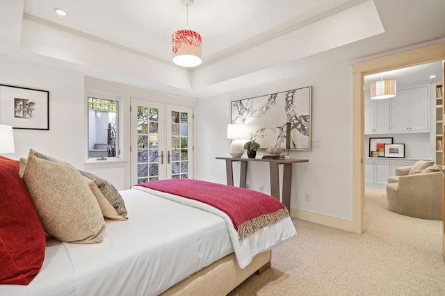 carpeted bedroom with a raised ceiling and french doors