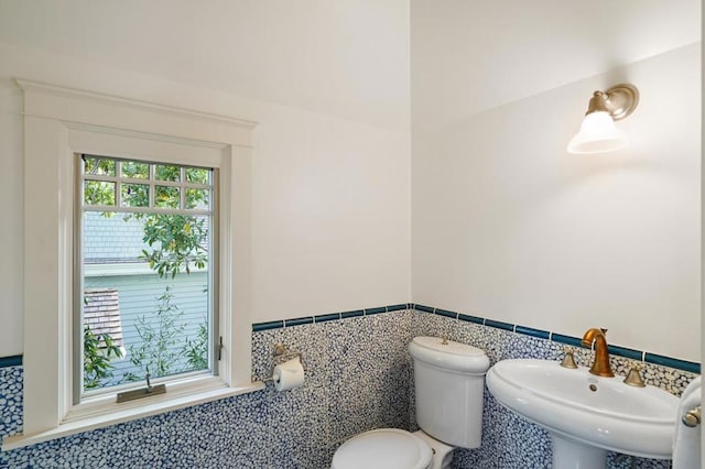 bathroom with toilet, a wealth of natural light, tile walls, and sink