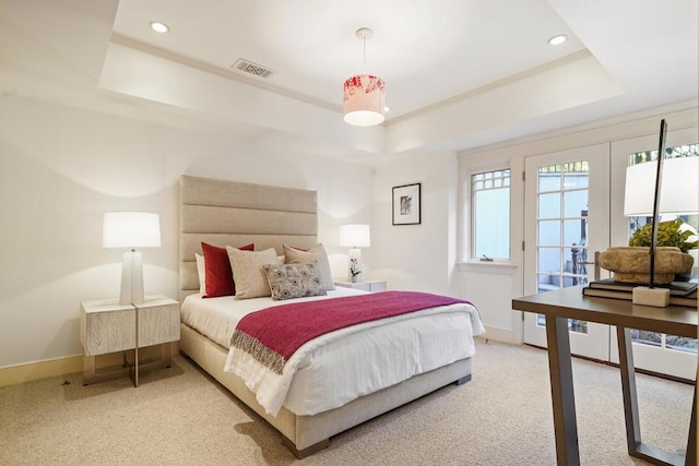 bedroom featuring light colored carpet and a tray ceiling