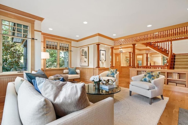 living room featuring ornamental molding, wood walls, light hardwood / wood-style flooring, and ornate columns