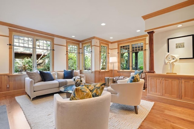 interior space featuring wooden walls, crown molding, ornate columns, and light hardwood / wood-style flooring