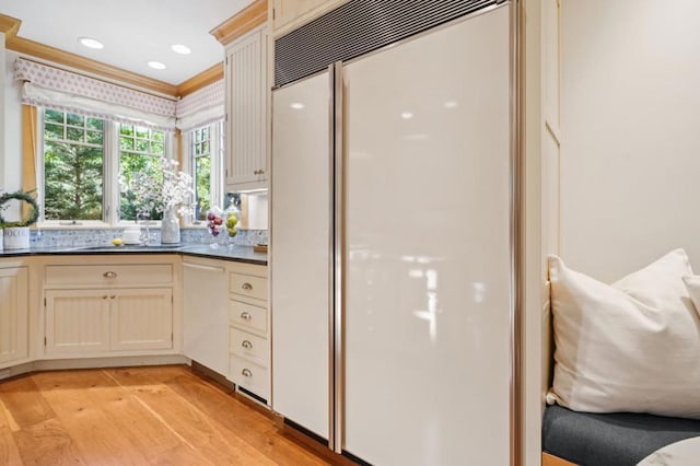 kitchen featuring built in fridge, ornamental molding, and light wood-type flooring