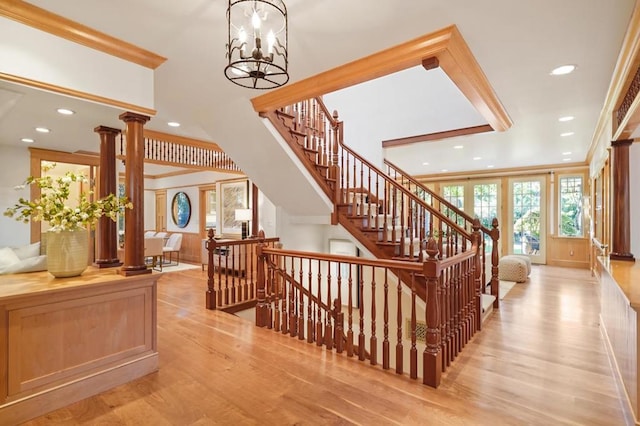 stairs featuring an inviting chandelier, crown molding, hardwood / wood-style flooring, and decorative columns