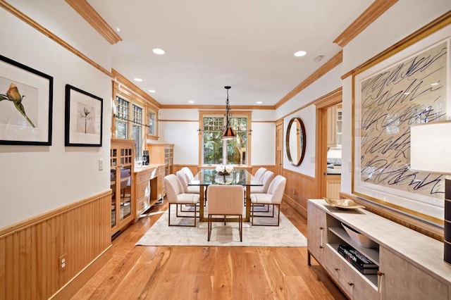 dining room featuring wood walls, light hardwood / wood-style flooring, and ornamental molding