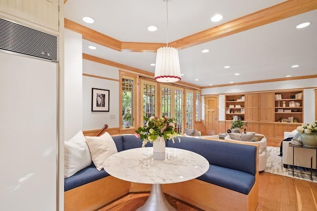 dining space with light hardwood / wood-style floors, built in features, and ornamental molding