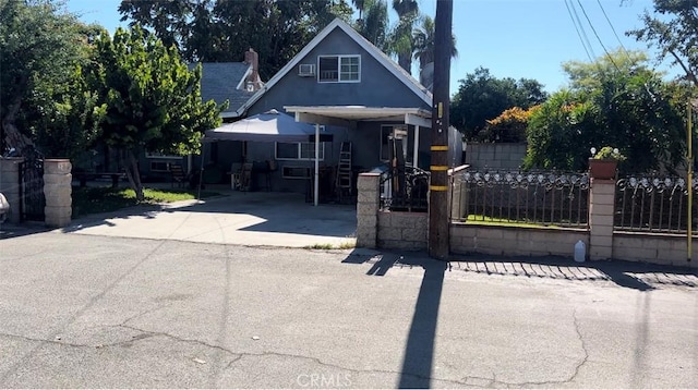 view of front of property featuring an AC wall unit and a fenced front yard